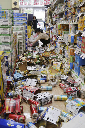 Employees try to remove bottles and cans of beverages which are scattered by an earthquake at a liquor shop in Hirakata, Osaka prefecture, western Japan, in this photo taken by Kyodo June 18, 2018. Mandatory credit Kyodo/via REUTERS ATTENTION EDITORS - THIS IMAGE WAS PROVIDED BY A THIRD PARTY. MANDATORY CREDIT. JAPAN OUT. NO COMMERCIAL OR EDITORIAL SALES IN JAPAN.