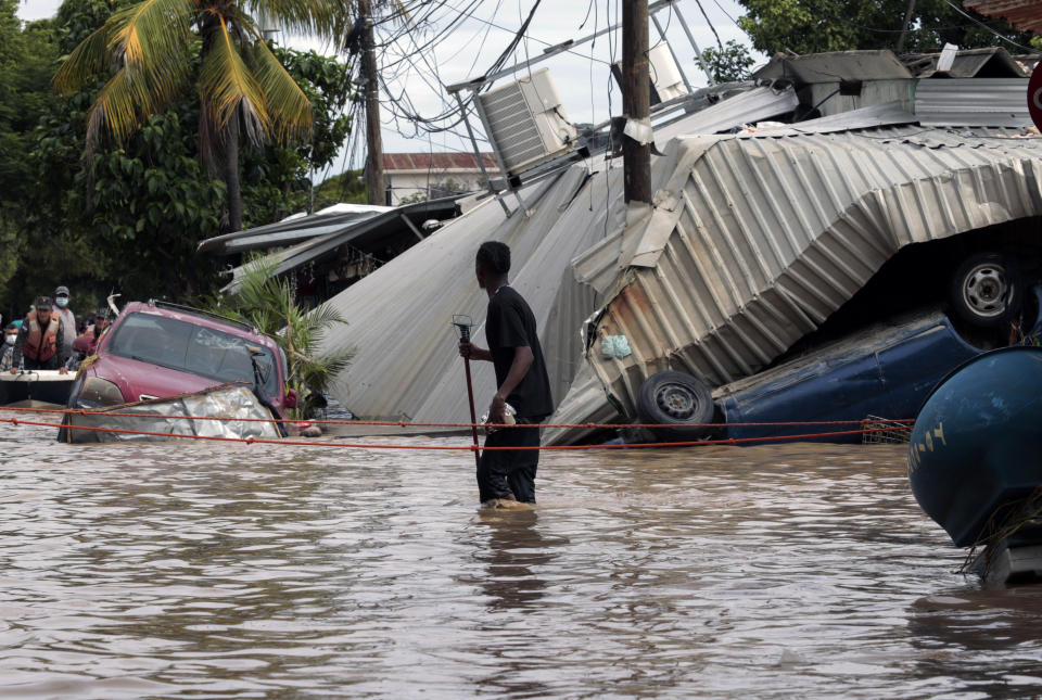 ARCHIVO - En esta foto de archivo del 6 de noviembre de 2020, un residente que camina por una calle inundada observa los daños causados ​​por el huracán Eta en Planeta, Honduras. Las familias hondureñas y guatemaltecas inundadas que quedaron varadas en los tejados de los barrios más marginados tras el paso de los huracanes Eta e Iota presagian una nueva ola de migración, según observadores de la región. (AP Foto/Delmer Martínez, Archivo)