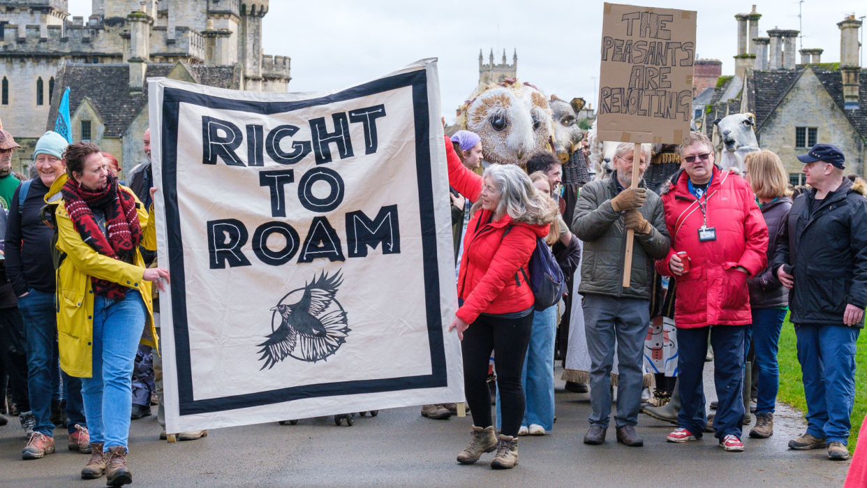  Protesters holding a banner that says 'right to roam' walk through Cirencester park. 