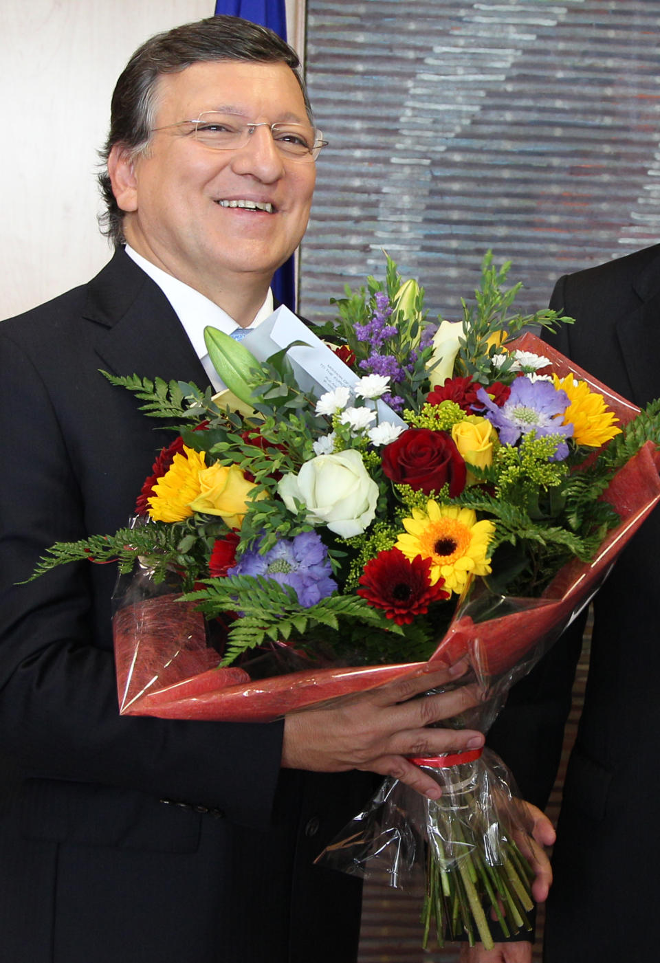 European Commission President Jose Manuel Barroso reacts, as he received flowers by Norway's ambassador to the EU Atle Leikvoll, after the 2012 Nobel Peace Prize was given to the EU, at the European Commission headquarters in Brussels, Friday, Oct. 12, 2012. The European Union won the Nobel Peace Prize on Friday for its efforts to promote peace and democracy in Europe, an award given even though the bloc is struggling with its biggest crisis since it was created in the 1950s. (AP Photo/Yves Logghe)