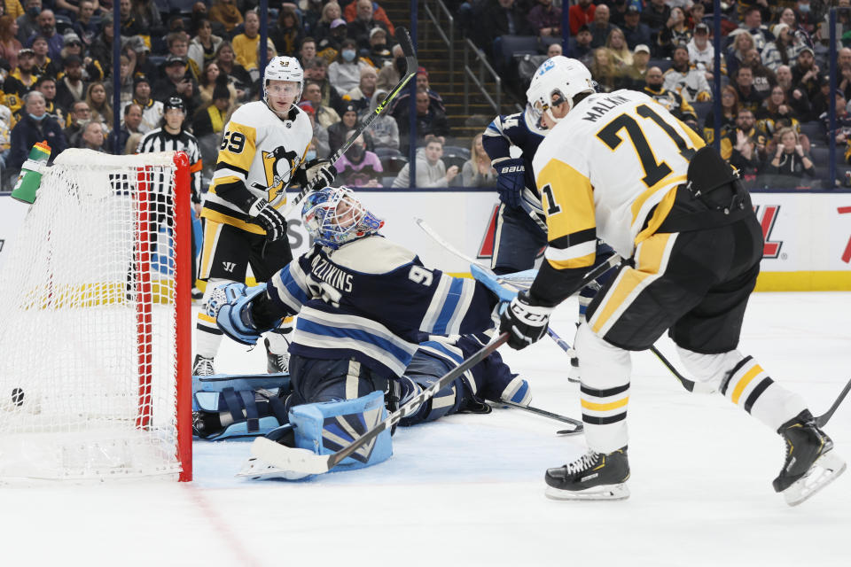 Pittsburgh Penguins' Evgeni Malkin, right, scores a goal against Columbus Blue Jackets' Elvis Merzlikins, front left, during the third period of an NHL hockey game Sunday, Feb. 27, 2022, in Columbus, Ohio. (AP Photo/Jay LaPrete)