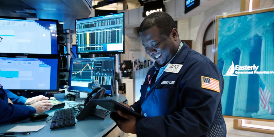 A smiling trader works on the floor of the New York Stock Exchange.