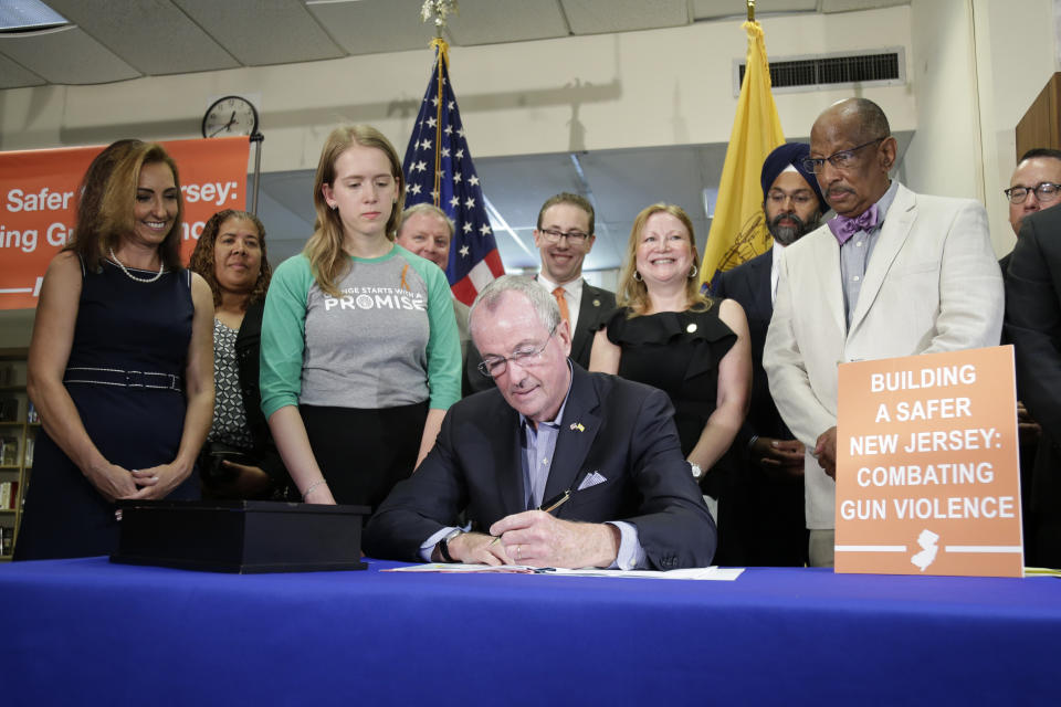 New Jersey Gov. Phil Murphy, center, signs a gun control bill during a ceremony in Berkeley Heights, N.J., Tuesday, July 16, 2019. Murphy has signed a measure aimed at making so-called smart guns available in the state. He also signed three other measures aimed at reining in gun violence. (AP Photo/Seth Wenig)