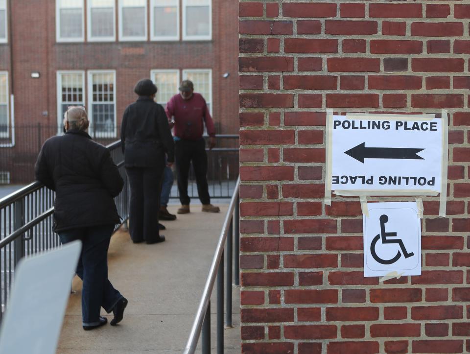 A handful of people wait outside of a polling site at Harlan Elementary School in Wilmington to vote on Tuesday.