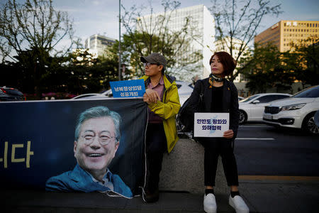 A woman holds a placard that reads "Peace, reconciliation and cooperation on the Korean peninsula" during a rally to wish for a successful inter-Korean summit, in central Seoul, South Korea, April 21, 2018. REUTERS/Kim Hong-Ji