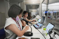 Interpreters work at the main press center during the 2020 Summer Olympics, Friday, July 30, 2021, in Tokyo, Japan. Unlike previous Olympics, all the interpretation is being done remotely with most interpreters working in booths at the main center. Their simultaneous translation can be accessed at all Olympic venues on an app. This eliminates interpreters getting tied up in traffic heading to an venue. (AP Photo/Luca Bruno)