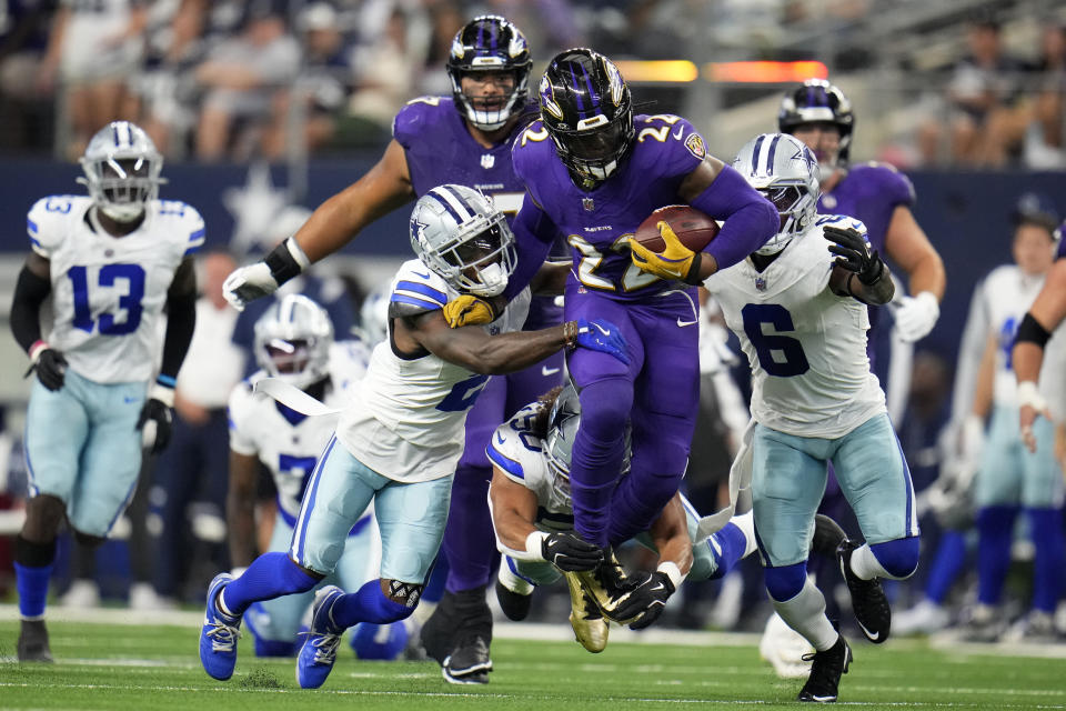 Baltimore Ravens running back Derrick Henry (22) runs the ball as Dallas Cowboys' Jourdan Lewis (2), Eric Kendricks, bottom, and Donovan Wilson (6) attempt to make the stop in the first half of an NFL football game in Arlington, Texas, Sunday, Sept. 22, 2024. (AP Photo/Julio Cortez)