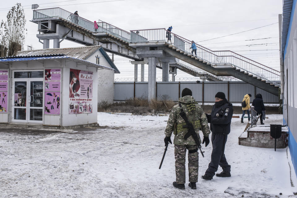 In this photo taken on Saturday, Dec. 1, 2018, Ukrainian policemen guard the side of the Ukraine-Russia border at a railway station in Milove, eastern Ukraine, one village, which is crossed by the national border. People on the streets easily mix both Russia and Ukrainian languages without making a political statement of it, but earlier this year, Russia built a barbed wire fence on the Friendship of People's street, marking the border with Ukraine in a metaphorical statement about the long-simmering conflict between the countries. (AP Photo/Evgeniy Maloletka)