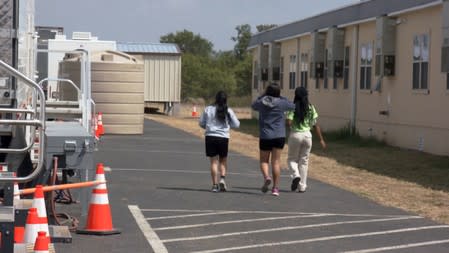 Youths walk at the HHS unaccompanied minors migrant detention facility at Carrizo Springs