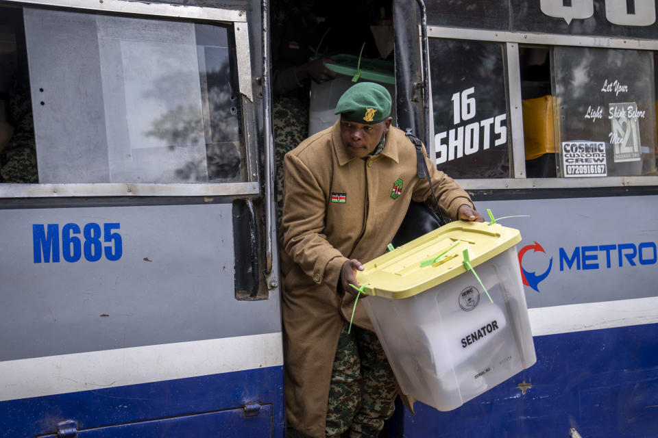 A member of the National Youth Service helps to offload electoral materials from a minibus transporting electoral workers to a collection and tallying center in Nairobi, Kenya Wednesday, Aug. 10, 2022. Kenyans are waiting for the results of a close but calm presidential election in which the turnout was lower than usual. (AP Photo/Ben Curtis)