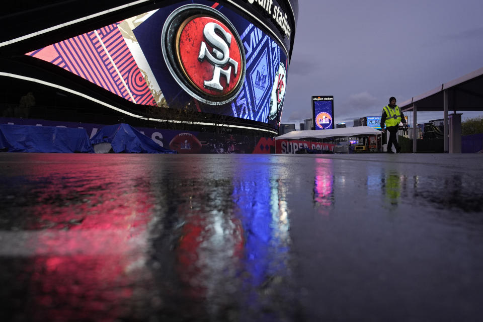 A security guard walks through light rain outside of Allegiant Stadium ahead of the Super Bowl football game, Thursday, Feb. 1, 2024, in Las Vegas. Las Vegas is scheduled to host the Super Bowl 58 on Sunday, Feb. 11, 2024. (AP Photo/John Locher)