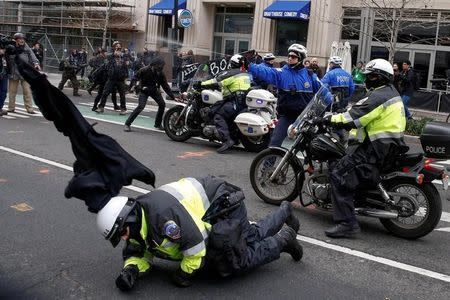 A police officer falls to the ground as another shoots pepper spray at protesters demonstrating against U.S. President Donald Trump on the sidelines of the inauguration in Washington, D.C. January 20, 2017. REUTERS/Adrees Latif/File Photo