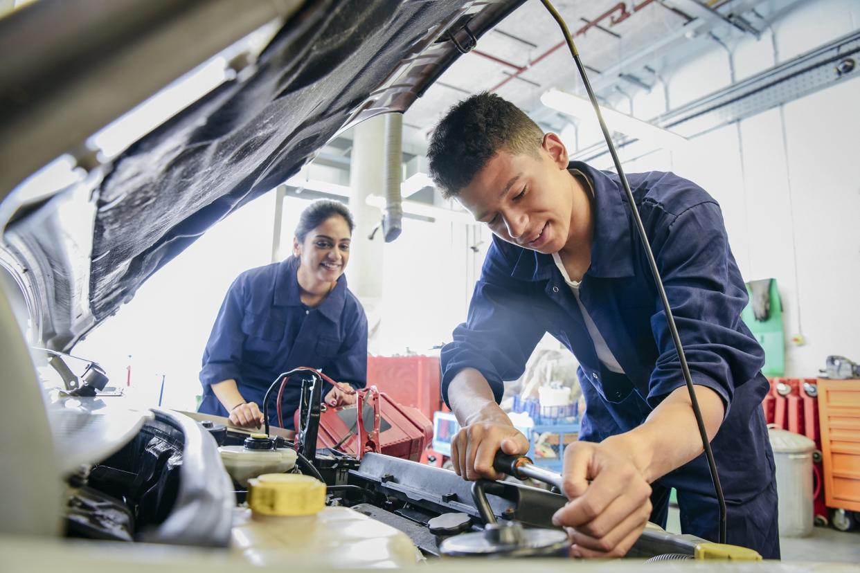 male student repairing car, woman watching