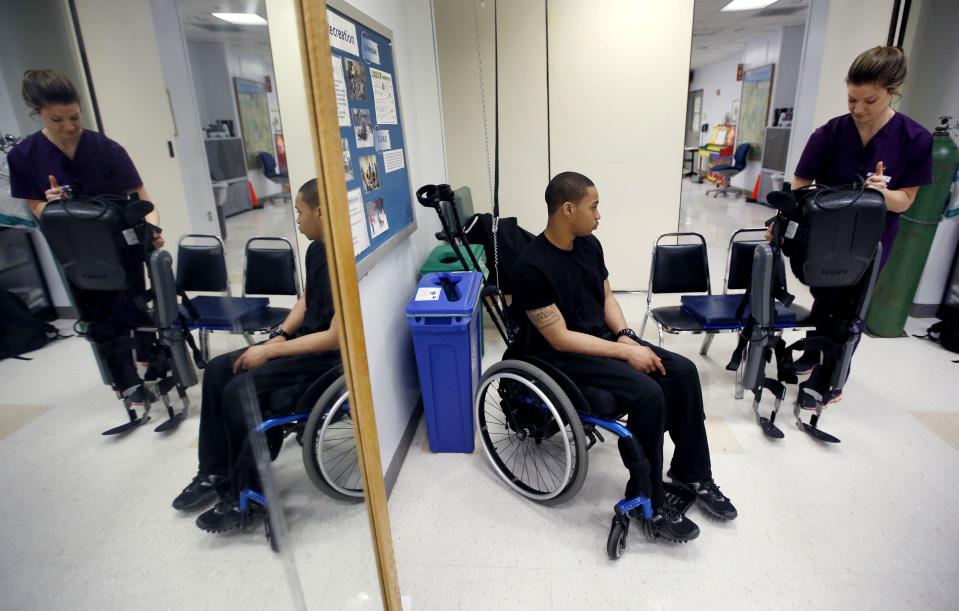 Samuels from Queens sits in his wheelchair as therapist Voigt prepares ReWalk electric powered exoskeletal suit for a therapy session with Samuels at the Mount Sinai Medical Center in New York City