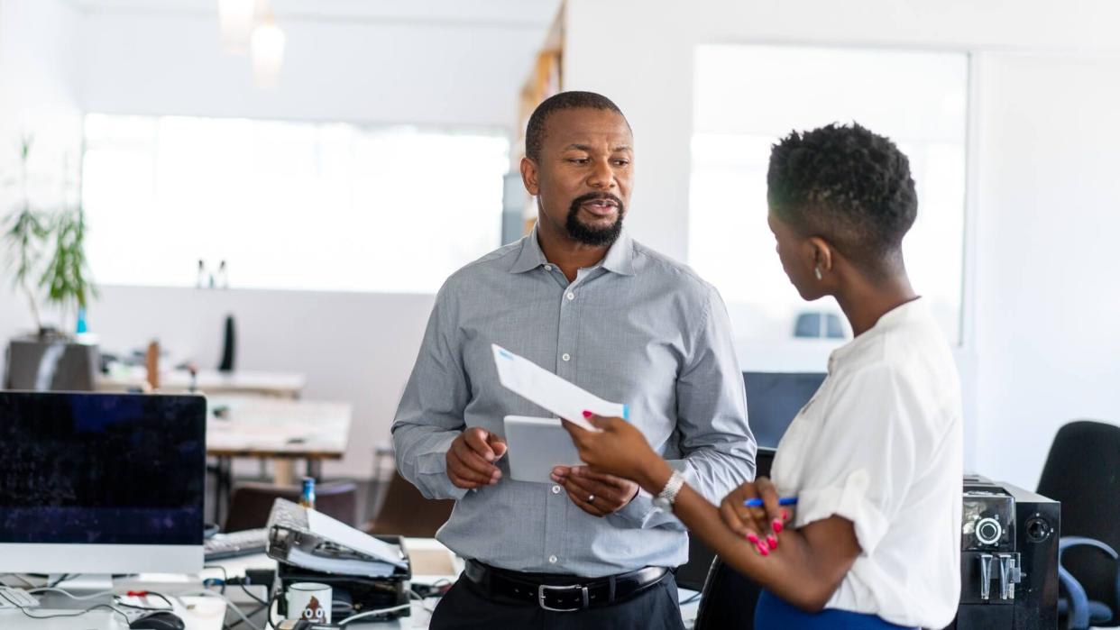 Confident business professionals discussing while standing in creative workplace.