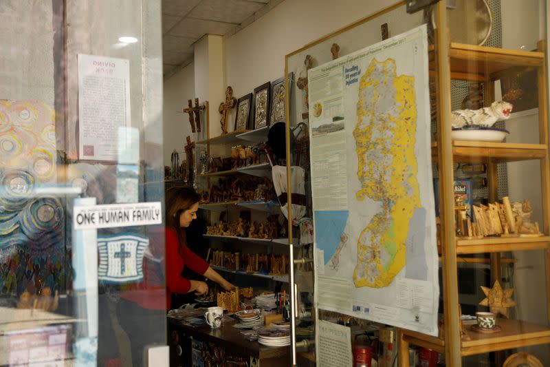 Palestinian woman arranges souvenirs carved from olive wood in a shop in Bethlehem in the Israeli-occupied West Bank