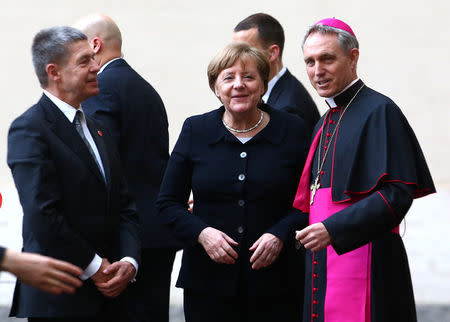 Archbishop Georg Ganswein greets German Chancellor Angela Merkel and her husband Joachim Sauer as they arrive for a meeting with Pope Francis at the Vatican March 24, 2017. REUTERS/Alessandro Bianchi