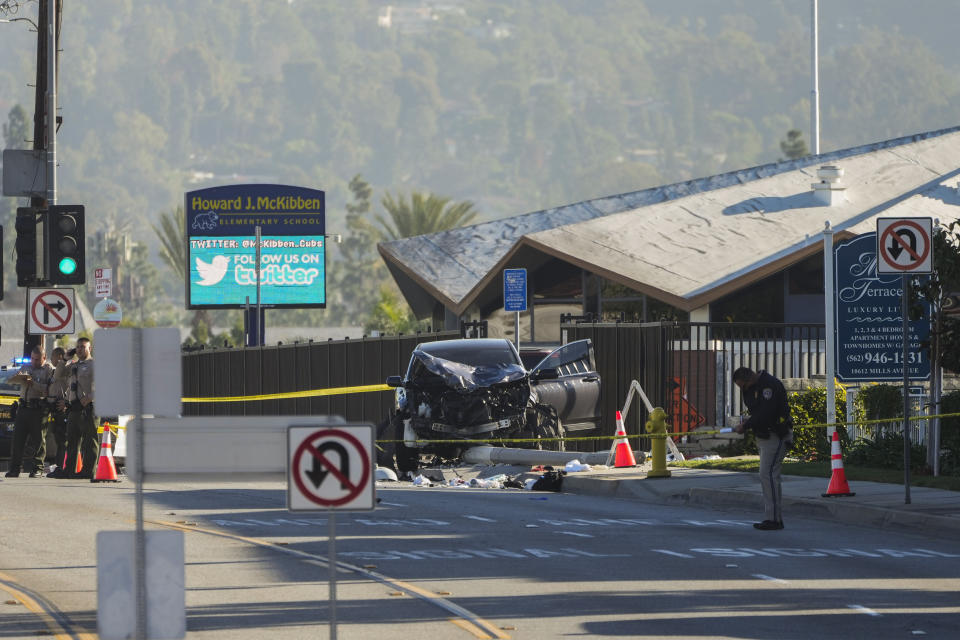 An investigator stands near a mangled SUV that struck Los Angeles County sheriff's recruits in Whittier, Calif., Wednesday, Nov. 16, 2022. The vehicle struck several Los Angeles County sheriff's recruits on a training run around dawn Wednesday, some were critically injured, authorities said. (AP Photo/Jae C. Hong)