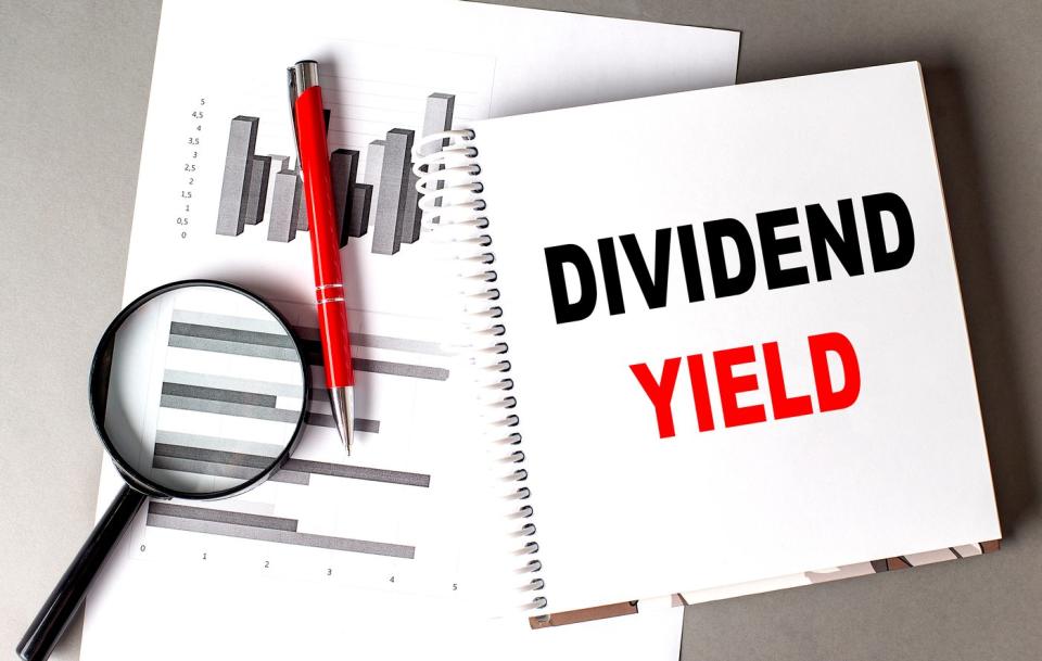 Charts, pen, magnifying glass, and notebook reading Dividend Yield.