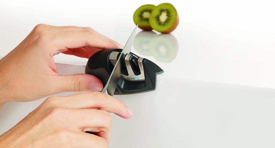 Someone using the small, handheld knife sharpener