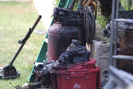 A burned tank is seen in the garden of a suburban home that was the site of a hash oil extraction laboratory explosion in the Mira Mesa area of San Diego