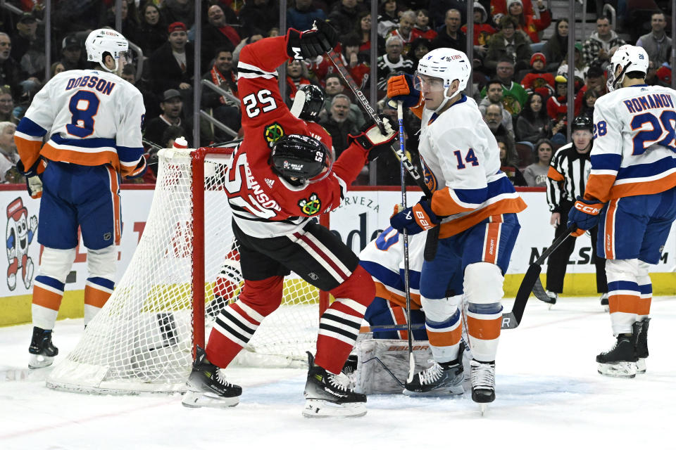 Chicago Blackhawks center Reese Johnson (52) and New York Islanders center Bo Horvat (14) fight for the puck during the first period of an NHL hockey game, Friday, Jan. 19, 2024, in Chicago. (AP Photo/Matt Marton)