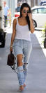 <p>The mother of three stepped out in Los Angeles wearing a simple white tank top and ripped lightwash jeans. She dressed up her casual look with a pair of round sunnies, a choker necklace, her go-to Cartier bangles, a monogram Louis Vuitton mini backpack, and nude heeled sandals.</p>