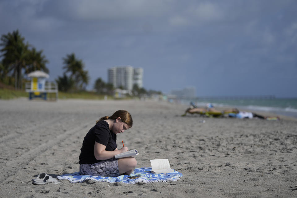 Eden Hebron, 19, writes in her journal on the beach near her parent's condominium, as she continues to work through the mental health effects years after witnessing a gunman kill a close friend and two other students in Florida's 2018 high school massacre in Parkland, Friday, March 11, 2022, while visiting her parents during her college's spring break, in Hollywood, Fla. Hebron's experience shows how many of the survivors have grappled with severe mental health issues that derailed their adolescence and greatly impacted their families.(AP Photo/Rebecca Blackwell)