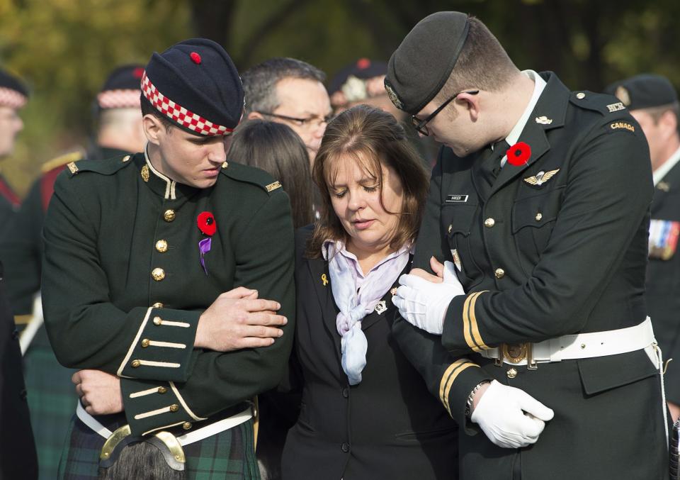 Kathy Cirillo is conforted by soldiers during the funeral procession for her son Cpl. Nathan Cirillo in Hamilton, Ontario, on Tuesday, Oct. 28, 2014. Cirillo was standing guard at the National War Memorial in Ottawa last Wednesday when he was killed by a gunman who went on to open fire on Parliament Hill before being shot down in a hail of bullets. (AP Photo/The Canadian Press, Frank Gunn)