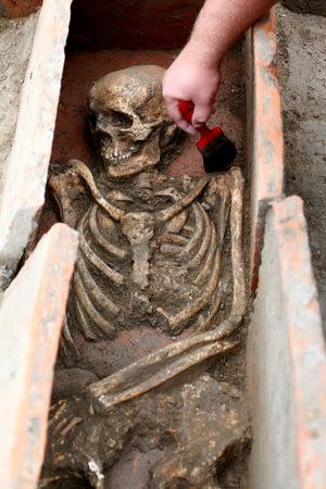 An archaeologist works over an uncovered skeleton at the Viminacium site, around 100km east from Belgrade, Serbia August 8, 2016. Picture taken August 8, 2016. REUTERS/Djordje Kojadinovic