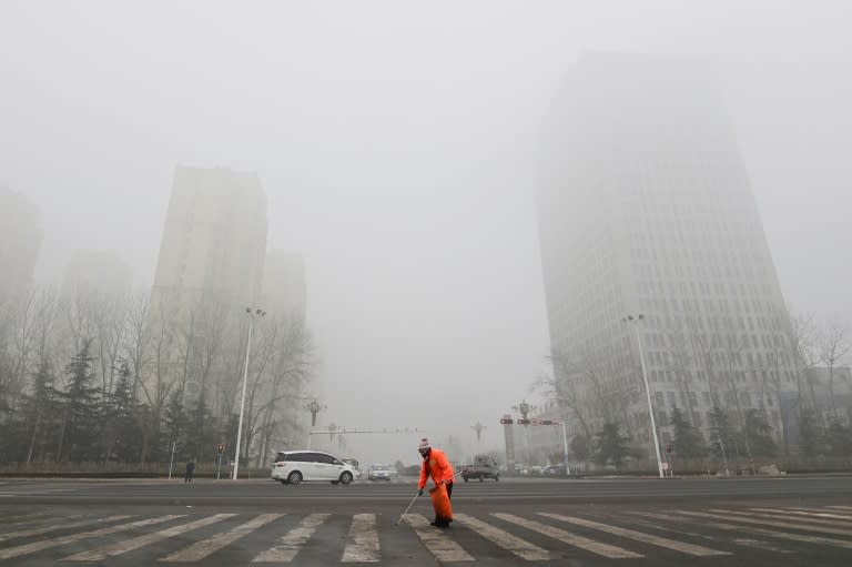 Un empleado de la limpieza trabaja en una calle de Qingzhou mientras la neblina y el aire contaminado envuelven los edificios de esa ciudad al este de China, el 28 de diciembre de 2023 (.)