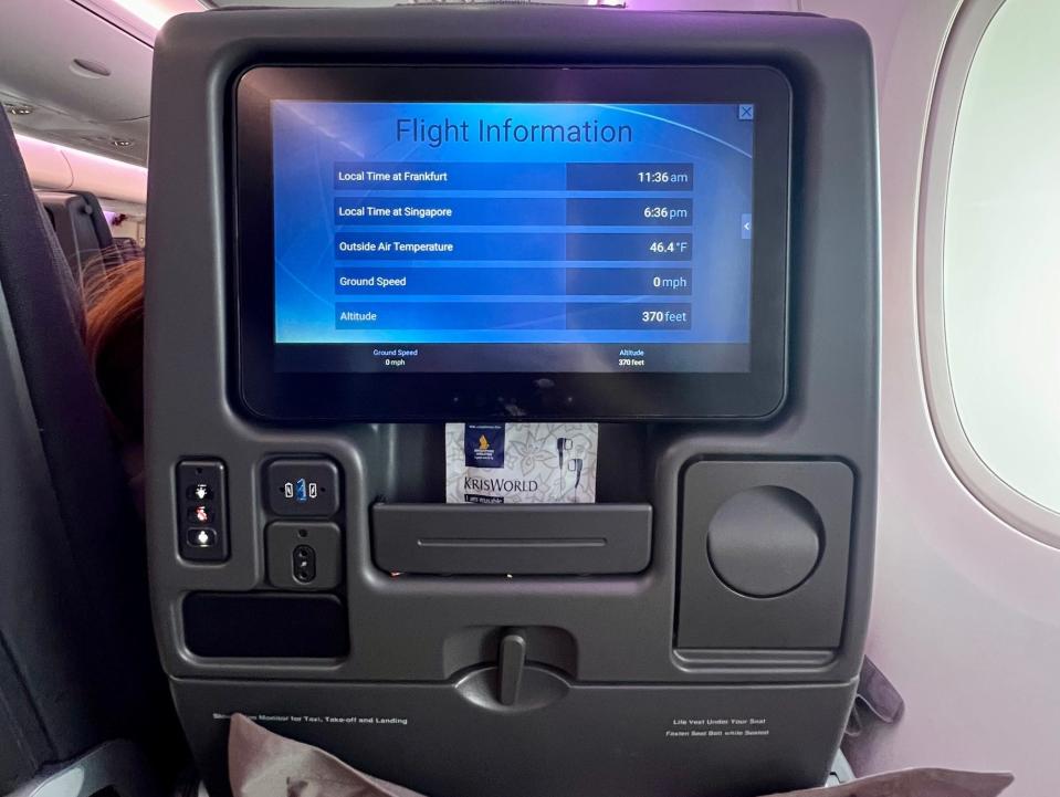 A view of the full seatback, with the TV, cupholder, USB, and cubby.