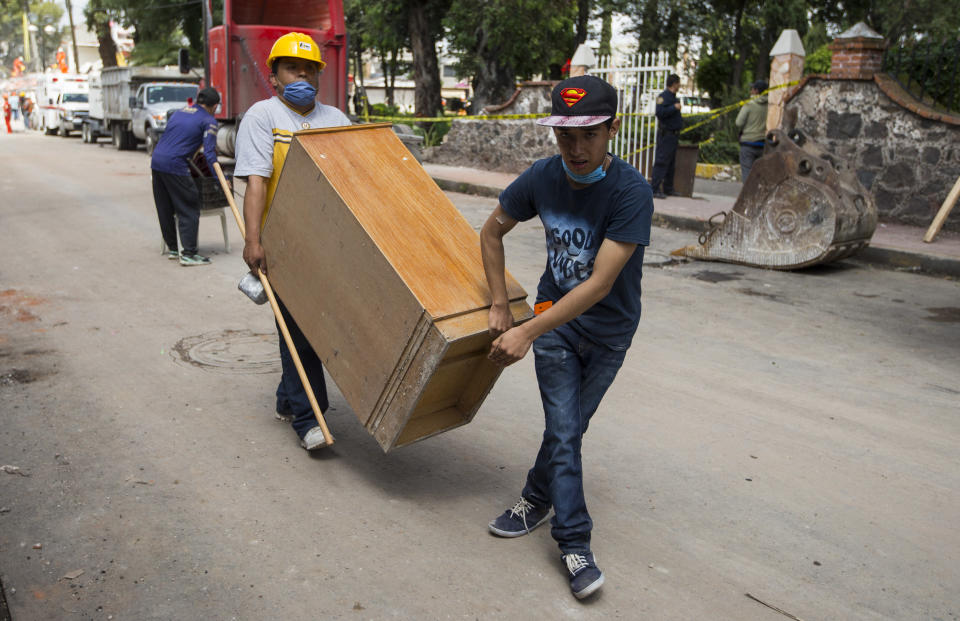 Neighbors carry a wooden cabinet from a building damaged by the 7.1-magnitude earthquake in San Gregorio Atlapulco, Mexico, Friday, Sept. 22, 2017. Mexican officials are promising to keep up the search for survivors as rescue operations stretch into a fourth day following Tuesday’s major earthquake that devastated Mexico City and nearby states. (AP Photo/Moises Castillo)