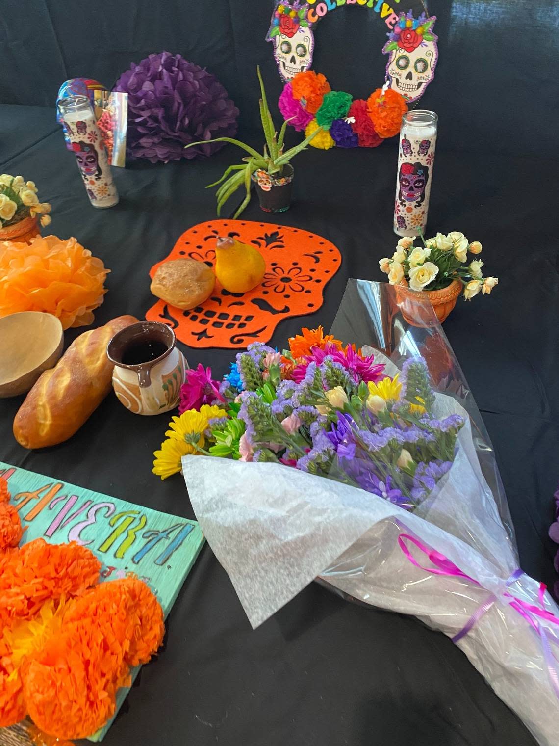 Food, flowers and art are some of the items placed on a community altar Saturday at the Eastside Community Center for Dia de los Muertos. 
