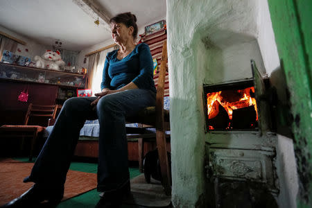 Pensioner Nadiya Ignatiy, 60, warms herself by a stove in her house in the village of Skryhalivka, Kiev region, Ukraine February 11, 2019. REUTERS/Gleb Garanich
