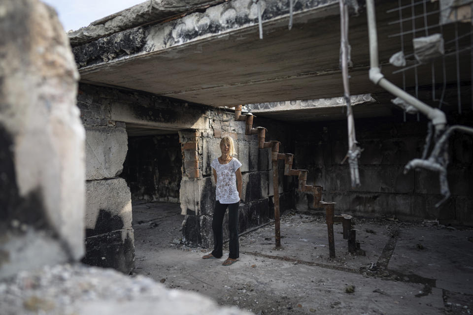 Zhanna Dynaeva stands inside her house which was destroyed by Russian bombardment, in the village of Novoselivka, near Chernihiv, Ukraine, Saturday, Aug. 13, 2022. Residents in many heavily-damaged areas in Ukraine have set up their own initiatives to rebuild homes before the winter as international organizations rush aid to Ukraine to help with the reconstruction effort. (AP Photo/Evgeniy Maloletka)