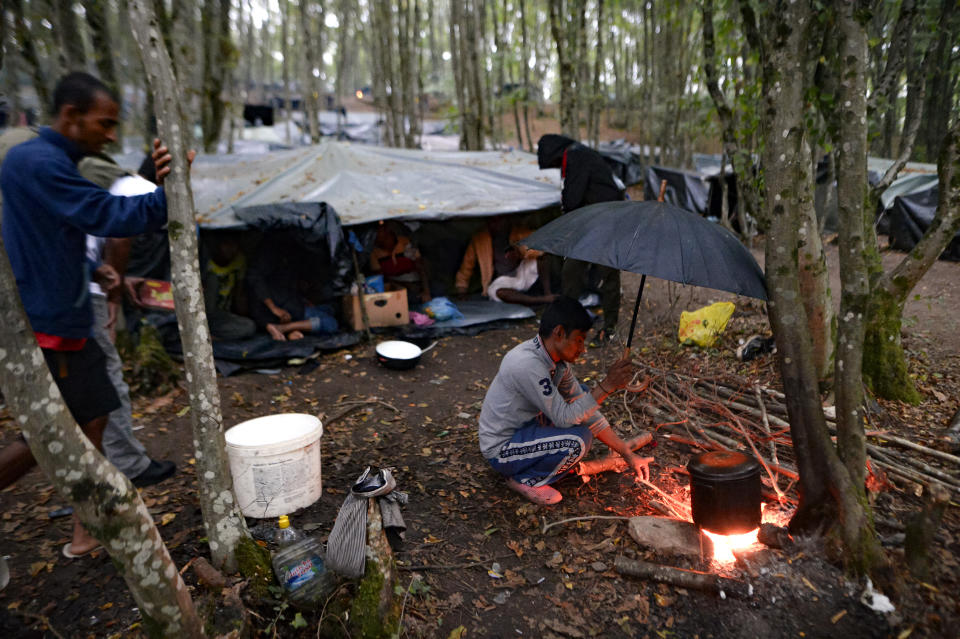 A migrant cooks on an open fire at a makeshift camp in a forest outside Velika Kladusa, Bosnia, Friday, Sept. 25, 2020.(AP Photo/Kemal Softic)