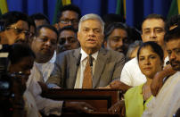 Sri Lanka's reinstated prime minister Ranil Wickeremesinghe, center, surrounded by his loyal lawmakers and supporters speaks after assuming duties in Colombo, Sri Lanka, Sunday, Dec. 16, 2018. Sri Lanka's president has reappointed Ranil Wickremesinghe as prime minister, nearly two months after firing him and setting off weeks of political stalemate. (AP Photo/Eranga Jayawardena)