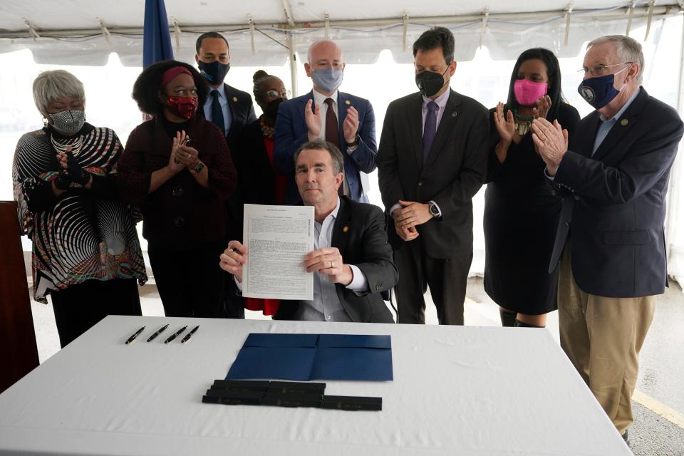 Virginia Gov. Ralph Northam, seated center, displays a bill abolishing the death penalty after signing it as he is surrounded by legislators and activists at Greensville Correctional Center in Jarratt, Va., Wednesday, March 24, 2021.