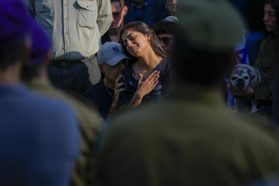 Mourners gather in grief around the grave of Israeli soldier Captain Harel Ittah during his funeral in Netanya, Israel, Sunday, Dec. 31, 2023. Ittah, 22, died of his wounds after he was injured while the army is battling Palestinian militants across Gaza in the war ignited by Hamas' Oct. 7 attack into Israel. (AP Photo/Ariel Schalit)