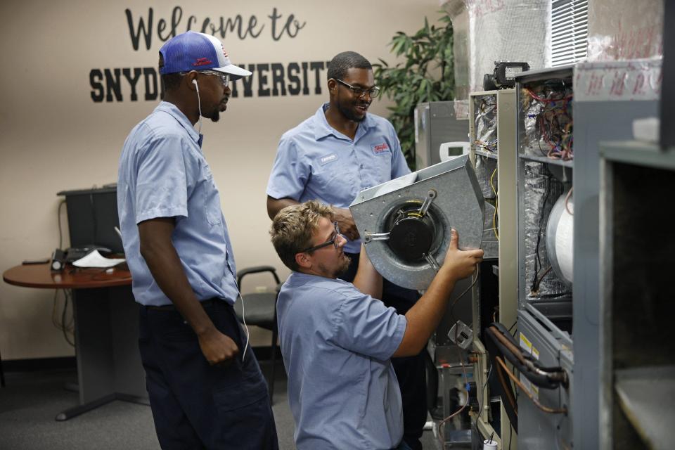 Thomas Nadeau, bottom, pulls out a blower to a residential air handler as Duine Henry, left, and Kenneth Brown watch on Aug. 10 at Snyder Air Conditioning, Plumbing & Electric in Jacksonville. A group of HVAC Technicians were part of a registered apprentice training program through Trade Up Academy and Snyder. The year-long program helps them transition from classroom work with light duties to full-fledged employee.