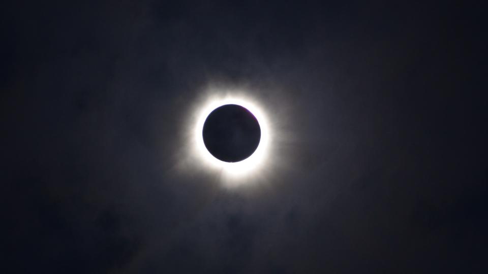 The sun's bright white corona is visible behind the moon on April 8, 2024