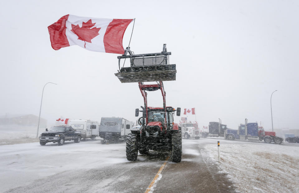 Anti-COVID-19 vaccine mandate demonstrators gather as a truck convoy blocks the highway at the busy U.S. border crossing in Coutts, Alberta, Canada, Monday, Jan. 31, 2022. (Jeff McIntosh/The Canadian Press via AP)