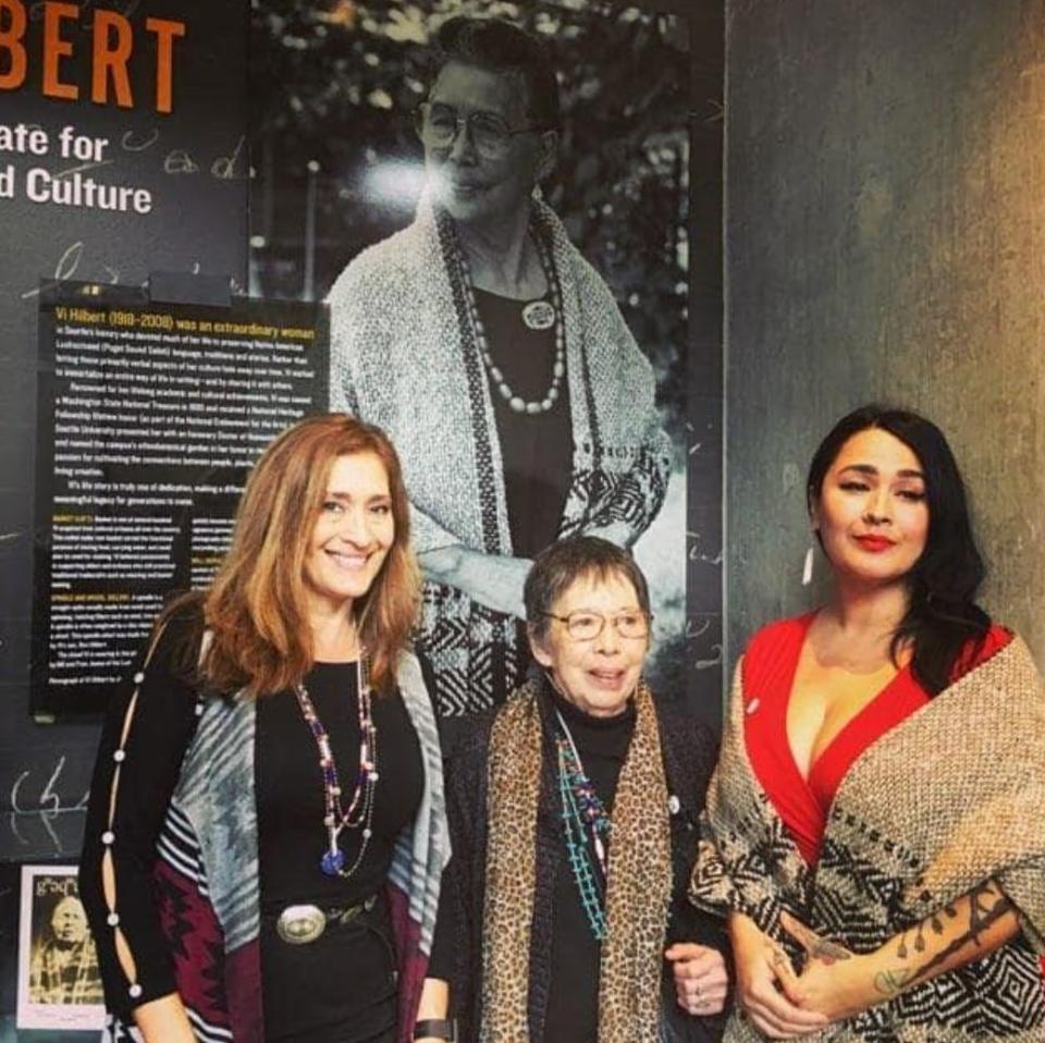 Four generations together at Seattle University in 2020. From left, Jill LaPointe (the author's mom), Lois Dodson (the author's grandmother), and the author. Vi taqʷ&scaron;əblu Hilbert (the author's great-grandmother) is in the painting behind them. (Photo: Courtesy of Sasha taqʷšəblu LaPointe)