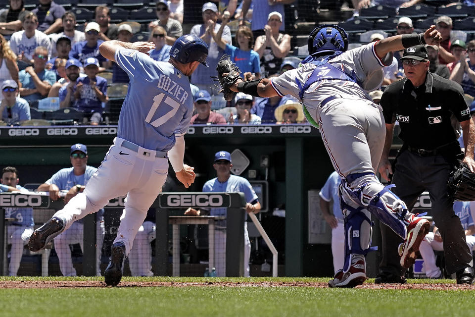 Kansas City Royals Hunter Dozier (17) is tagged out by Texas Rangers catcher Meibrys Viloria as he tried to score on a single by MJ Melendez during the first inning of a baseball game Wednesday, June 29, 2022, in Kansas City, Mo. (AP Photo/Charlie Riedel)