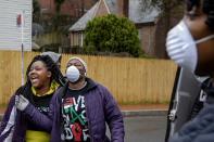 In this March 25, 2020, photo, Tonisha Wallace, left, and Regina Summers, both with the homegrown clothing company Never Black Down, share a joke during a break in food distribution next to India Blocker-Ford, of Indy B Mentoring, in southeast Washington. Neighborhood deliveries are part of a new Martha's Table initiative, along with community partners, to get needed food directly to the neighborhoods they serve. These local volunteers are the tip of the spear for a grassroots community effort to keep Washington's most vulnerable neighborhoods fed during the unprecedented coronavirus crisis which has nearly shut down the American economy. (AP Photo/Jacquelyn Martin)