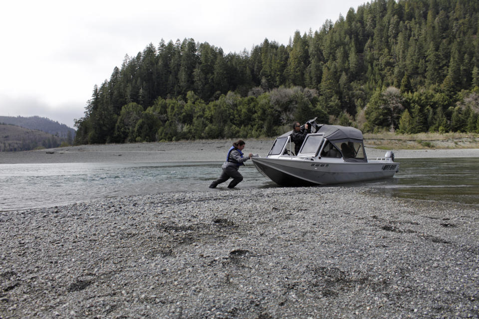 FILE - In this March 5, 2020, file photo, Hunter Maltz, a fish technician for the Yurok tribe, pushes a jet boat into the low water of the Klamath River at the confluence of the Klamath River and Blue Creek as Keith Parker, as a Yurok tribal fisheries biologist, watches near Klamath, Calif., in Humboldt County. One of the worst droughts in memory in the massive agricultural region straddling the California-Oregon border could mean steep cuts to irrigation water for hundreds of farmers this summer to sustain endangered fish species critical to local tribes. The U.S. Bureau of Reclamation, which oversees water allocations in the federally owned Klamath Project, is expected to announce this week how the season's water will be divvied up after delaying the decision a month. (AP Photo/Gillian Flaccus, File)