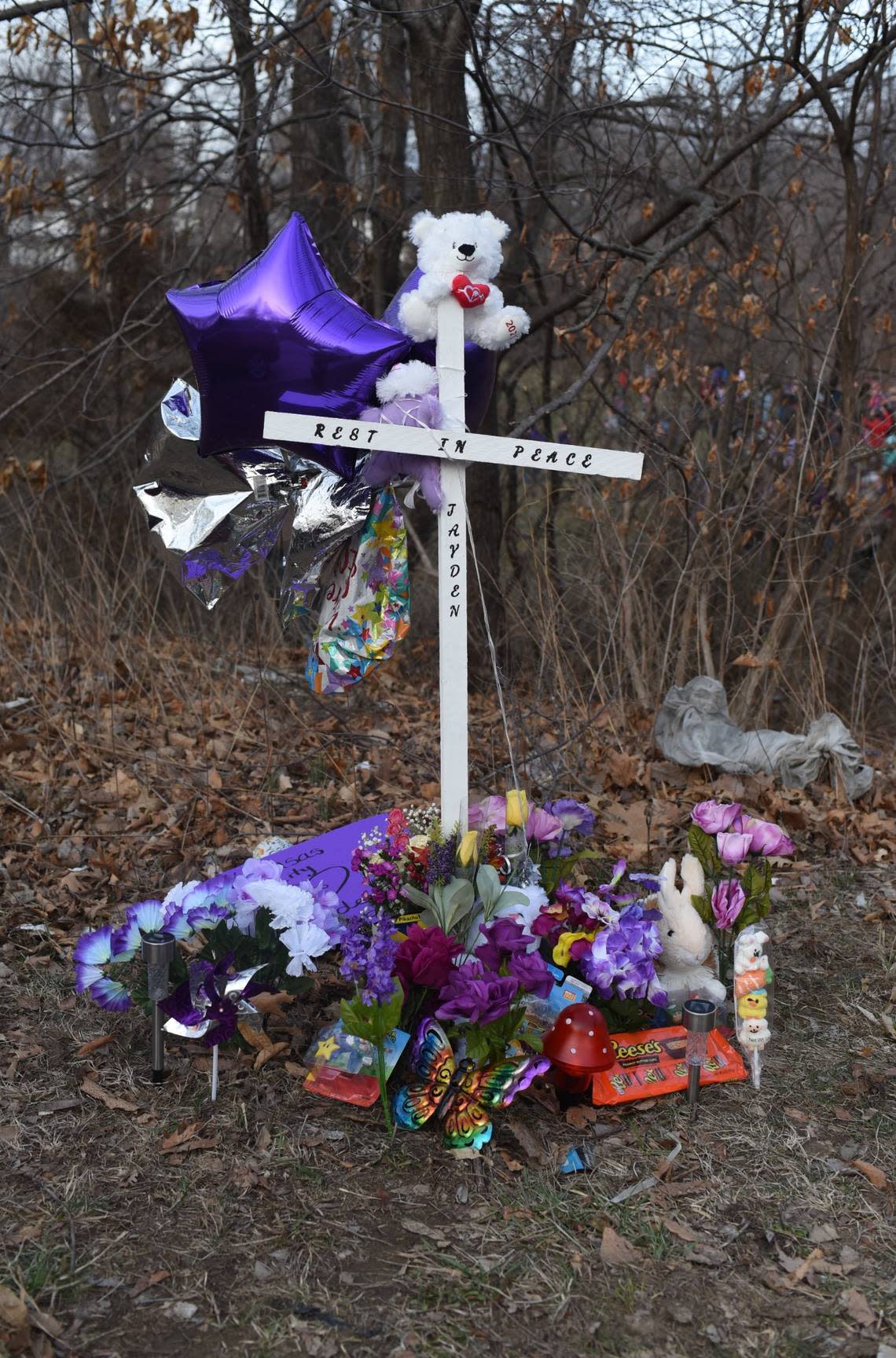 A cross sits surrounded by tributes to Jayden Robker, a missing Kansas City 13-year-old whose body was found Friday in a pond in Gladstone. Robker had been missing since early February Bill Lukitsch