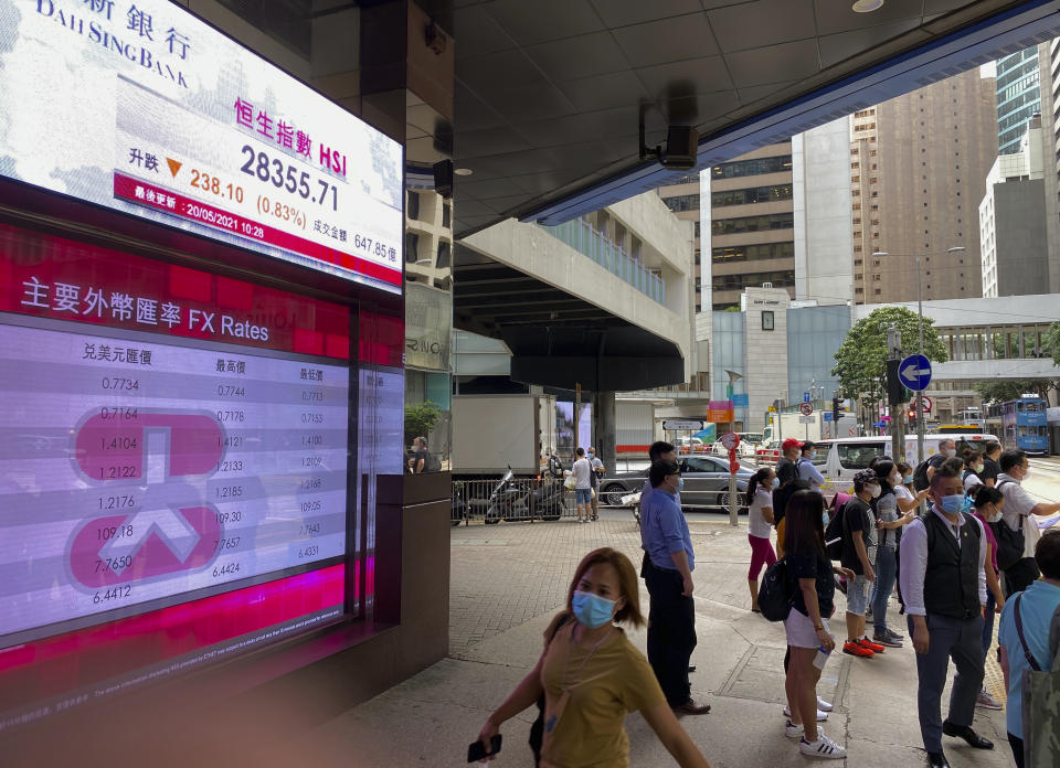 People stand near a bank's electronic board showing the Hong Kong share index at Hong Kong Stock Exchange Thursday, May 20, 2021. Shares were mixed in Asia on Thursday after benchmarks closed broadly lower on Wall Street in a third day of retreat. (AP Photo/Vincent Yu)