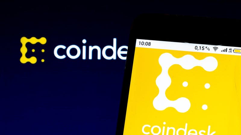 The CoinDesk logo behind a phone also showing the coindesk logo.